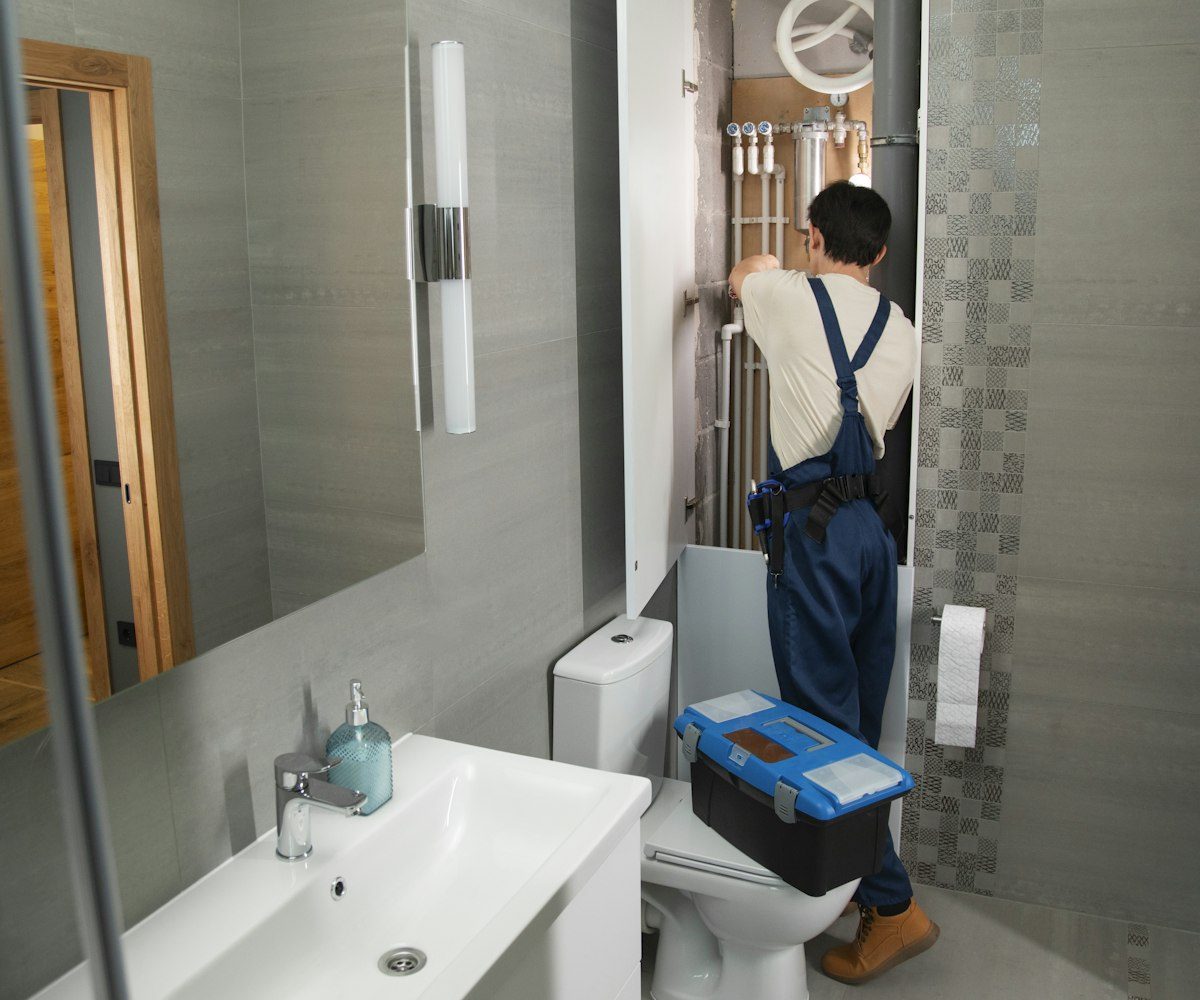 Plumber working on exposed plumbing in a bathroom